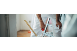 Schilder in witte kleding met een roller in zijn hand 