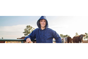Boer in blauwe overall met koeën op de achtergrond 