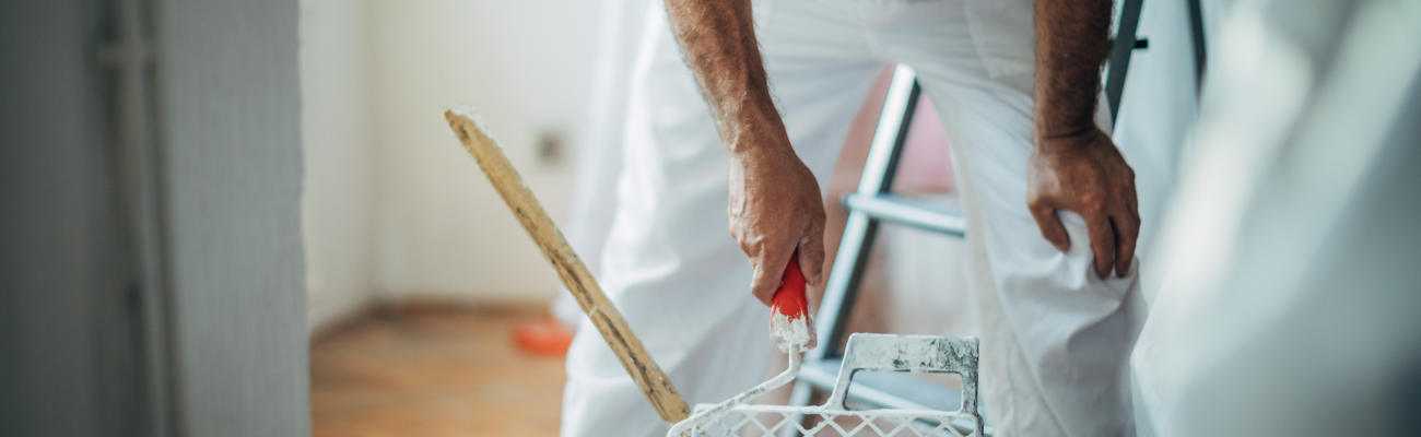 Schilder in witte kleding met een roller in zijn hand 